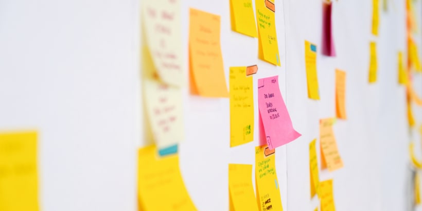 Orange and pink sticky notes on a white wall.